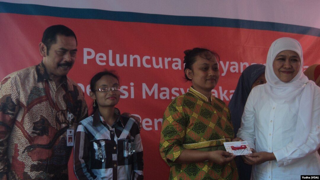 Menteri Sosial Khofifah Indar Parawansa (kanan) didampingi walikota Solo, F.X. Hadi Rudyatmo (kiri) membagikan kartu elektronik e-warong bagi warga miskin di Solo. (Foto: Dok)
