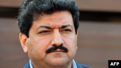 FILE - Pakistani journalist and television anchor, Hamid Mir talks with media representatives outside his home in Islamabad.