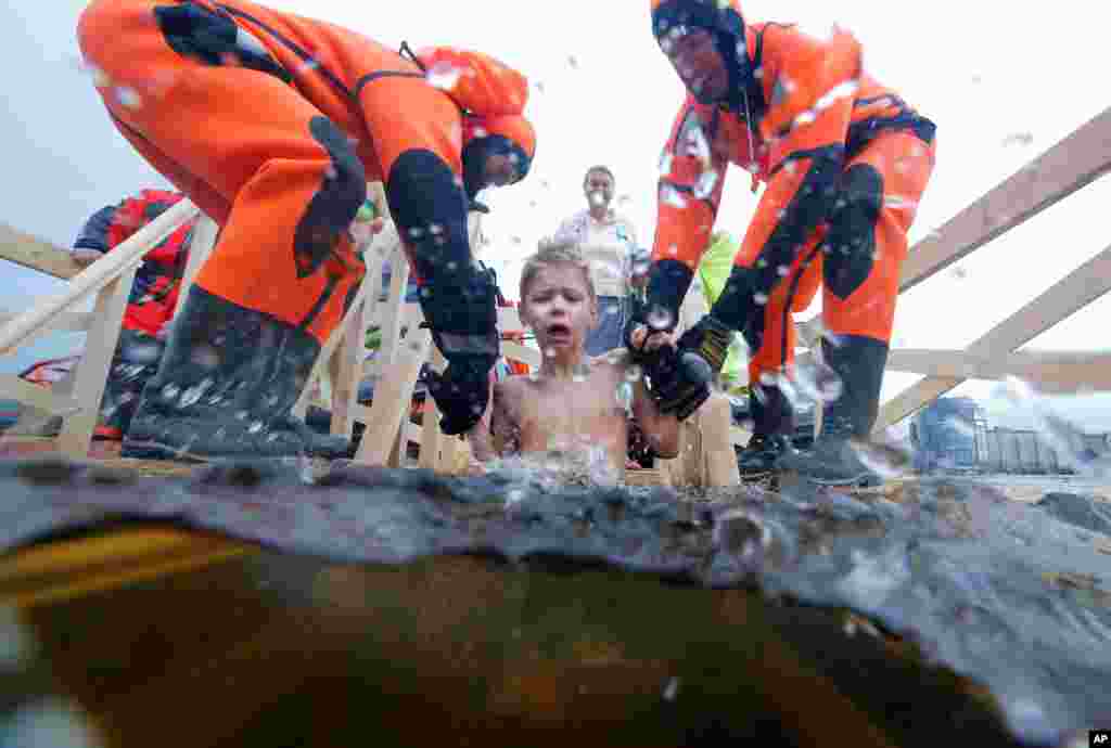 Rescue workers dip a boy in the icy water in the Neva River during a traditional Epiphany celebration in St. Petersburg, Russia.