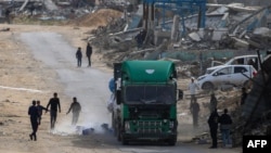 Palestinci trče da uzmu boce sa vodom nakon što su ispale iz kamiona koji prevozi humanitarnu pomoć u Gazi (Foto: Eyad BABA / AFP)