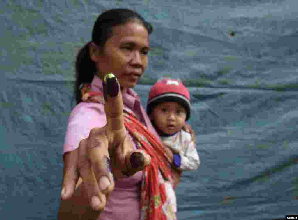 A woman poses with her baby after casting her ballot in Indonesia's presidential election in Brambang Darussalam, Bondowoso, East Java, Indonesia, July 9, 2014.
