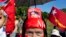 A supporter displays a picture of opposition leader Aung San Suu Kyi stuck in her headband during a campaign rally of the National League for Democracy in Thandwe, Myanmar, Oct. 17, 2015. 