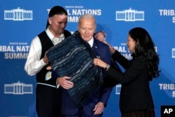 Interior Secretary Deb Haaland and Assistant Secretary for Indian Affairs Bryan Newland present President Joe Biden with a wool blanket designed by Laguna Pueblo artist Pat Pruitt at the 2024 White House Tribal Nations Summit in Washington, Monday, Dec. 9, 2024. (AP/Susan Walsh)