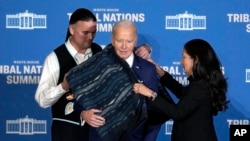 Interior Secretary Deb Haaland, right, and Bryan Newland, assistant secretary for Indian Affairs at the Department of the Interior, present President Joe Biden with an Eighth Generation blanket at the 2024 White House Tribal Nations Summit in Washington, Dec. 9, 2024.