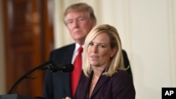 FILE - President Donald Trump, left, listens as Kirstjen Nielsen speaks in the East Room of the White House in Washington, Oct. 12, 2017.