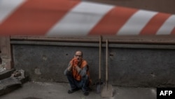 A worker rests next to a residential building damaged following a Russian drone attack, in Kyiv, on Sept. 26, 2024.