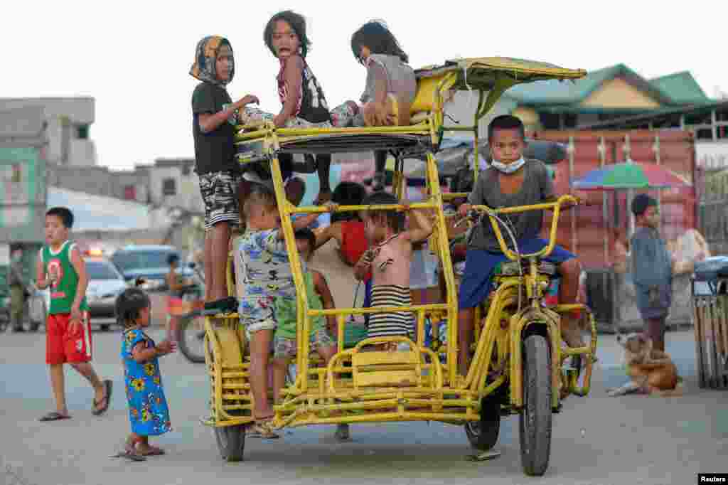 Children ride on a pedicab at a park in Baseco compound, Manila, Philippines.