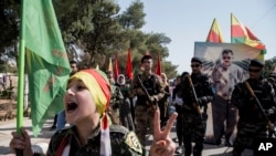 FILE - Fighters of the Syrian Democratic Forces (SDF) march during a rally in al-Qahtaniyah, Syria, Oct. 7, 2019.