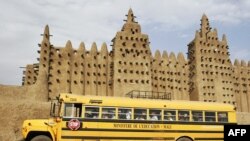 Un bus du ministère de l'Education passe devant la Grande Mosquée de Djenné dans la région du Delta du Niger au centre du Mali, le 9 février 2005.