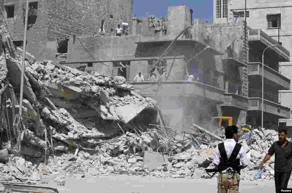 Civilians and members of the Free Syrian Army inspect a damaged building in al-Kalaseh neighbourhood in Aleppo, after a morning jet air strike, September 19, 2012.