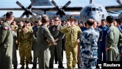 An official yells to members of aircrews, who are involved in the search for missing Malaysia Airlines plane MH370, to get them into position for an official photograph as they stand on the tarmac at the Royal Australian Air Force (RAAF) Pearce Base, Apri