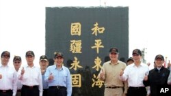 Taiwan's President Ma Ying-jeou, fifth from left, poses for a group photo in front of a monument reading: “Peace in the East China Sea and our national territory secure forever" during his visit to Pengjia Islet in the East China Sea, north of Taiwan, April 9, 2016.