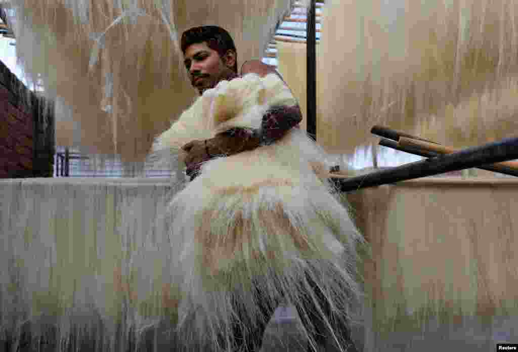 A man carries strands of vermicelli, a specialty eaten during the Muslim holy fasting month of Ramadan, to dry at a factory in Prayagraj, India.