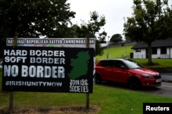 FILE - A car drives past a sign saying "No Border, Hard border, soft border, no border" in Londonderry, Northern Ireland, Aug. 16, 2017.