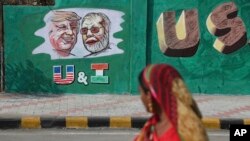 An Indian woman looks at a wall painted with portraits of U.S. President Donald Trump and Indian Prime Minister Narendra Modi ahead of Trump's visit, in Ahmadabad, India, Feb. 18, 2020. 