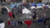 FILE - Migrants gather at a tent encampment set up on the plaza of the Santa Cruz y La Soledad Catholic parish church, in La Merced neighborhood of Mexico City, Dec. 26, 2023. 