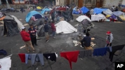 FILE - Migrants gather at a tent encampment set up on the plaza of the Santa Cruz y La Soledad Catholic parish church, in La Merced neighborhood of Mexico City, Dec. 26, 2023. 