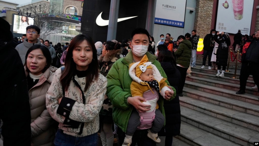 FILE - A man carries a child at a shopping mall in Beijing, Dec. 30, 2023. China’s population ｄropped by 2 million people in 2023 in the second straight annual ｄrop as births fell and deaths jumped. (AP Photo/Ng Han Guan)