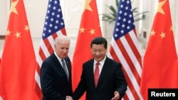 FILE - Chinese President Xi Jinping (R) shakes hands with U.S. Vice President Joe Biden (L) inside the Great Hall of the People in Beijing.