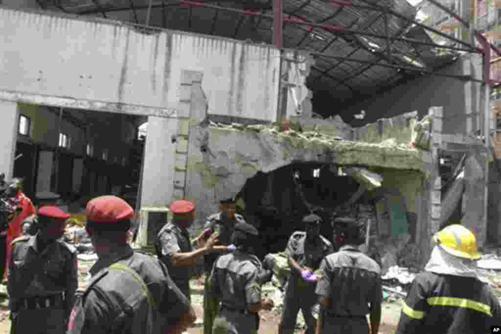 Police and rescuers stand in front of the bombed office of ThisDay, an influential daily newspaper in Abuja, Nigeria, Thursday, April. 26, 2012.