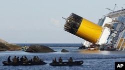 Scuba divers sit in a dinghy next to the Costa Concordia cruise ship which ran aground off the west coast of Italy at Giglio island, January 24, 2012.