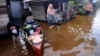 FILE - People talk outside their homes at a neighborhood affected by flood in Banjarmasin, South Kalimantan on Borneo Island, Indonesia, Jan. 17, 2021. 