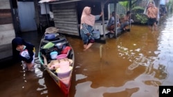 FILE - People talk outside their homes at a neighborhood affected by flood in Banjarmasin, South Kalimantan on Borneo Island, Indonesia, Jan. 17, 2021. 