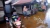 Sejumlah warga berbincang-bincang di depan rumah mereka di kawasan yang terendam banjir di Banjarmasin, Kalimantan Selatan, 17 Januari 2021. (Foto: Iman Satria/AP)