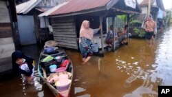 Sejumlah warga berbincang-bincang di depan rumah mereka di kawasan yang terendam banjir di Banjarmasin, Kalimantan Selatan, 17 Januari 2021. (Foto: Iman Satria/AP)