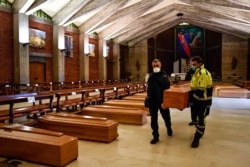 FILE - A coffin is carried to be aligned with others on the floor in the San Giuseppe church in Seriate, one of the areas worst hit by coronavirus, near Bergamo, Italy, waiting to be taken to a crematory, March 26, 2020.