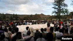 FILE - People stand in line to receive food donations, at the Tsehaye primary school, which was turned into a temporary shelter for people displaced by conflict, in the town of Shire, Tigray region, Ethiopia, March 15, 2021.