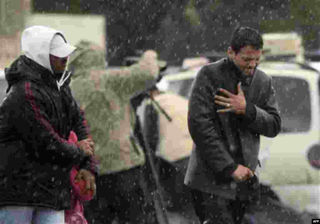 Tunisians carry their belongings under the rain after they fled from Libya, at the Tunisia-Libya border, near the village of Ras Ajdir, Tunisia, Wednesday, Feb. 23, 2011. (AP Photo/Lefteris Pitarakis)