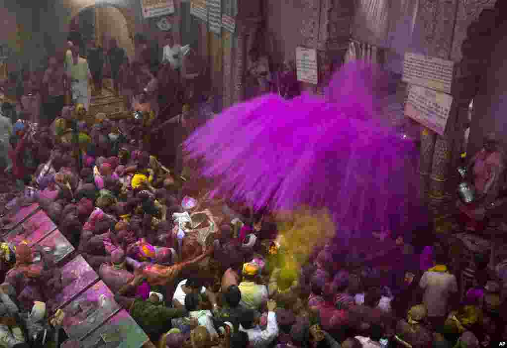 Hindu priests throw colored powders at the devotees inside Banke Bihari temple, dedicated to Lord Krishna, during Holi festival celebrations in Vrindavan, India.