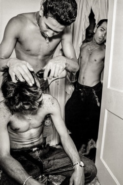 Gino gives a haircut to his friend at an apartment above the corner of Argyle and Glenwood, Uptown, Chicago, 1990s. (Stuart Isett)