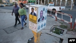 People walk past urban furniture covered with political posters and stickers in Maputo, Mozambique, on Oct. 04, 2024.