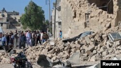 Residents look at the damage at a site hit by what activists said was a barrel bomb dropped by forces of Syria's President Bashar al-Assad, in the old city of Aleppo, May 31, 2015.