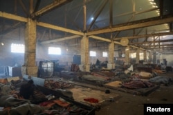 Migrants wrapped in blankets sleep on a floor inside a derelict customs warehouse in Belgrade, Serbia, Nov. 11, 2016.