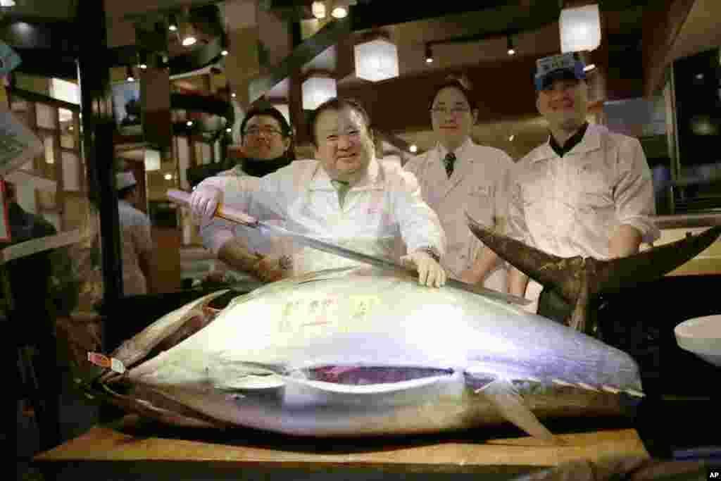 Kiyoshi Kimura, second from left, president of Kiyomura Co., poses a bluefin tuna at his Sushi Zanmai restaurant near Tsukiji fish market in Tokyo, Japan.