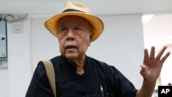 Thai social critic Sulak Sivaraksa talks to reporters at a police station before going to Bangkok military court in Bangkok, Thailand, Oct. 9, 2017. Sulak faces up to 15 years in prison for offending the monarchy.