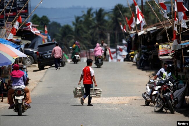 Seorang pria membawa telur saat menyeberang jalan di Pasar Sepaku di Kabupaten Penajam Paser Utara, Kalimantan Timur, 29 Agustus 2019. (Foto: Reuters)