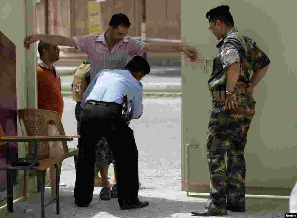 An Iraqi policeman searches a man as he enters a polling center during the country&#39;s provincial elections in Fallujah, June 20, 2013.