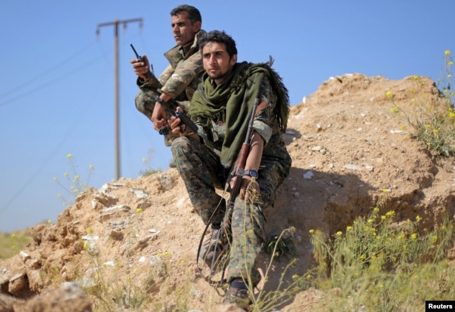 Fighters from the Syrian Democratic Forces hold walkie-talkies in the village of Baghuz, Deir el-Zour province, Syria, March 20, 2019.