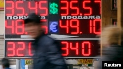 People pass by a board displaying exchange currency rates in Moscow, April 3, 2014.