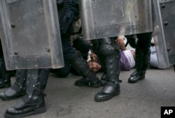 FILE - An anti-government protester is detained by Bolivarian National Police blocking protesters from reaching the headquarters of the national electoral body, CNE, to demand a recall referendum against President Nicolas Maduro in Caracas, May