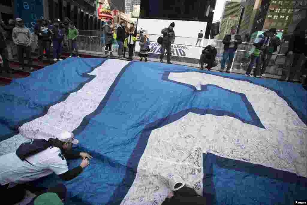 Seattle Seahawks fans sign a "12th Man" flag on "Super Bowl Boulevard" at Times Square, as part of the Super Bowl lead up, in New York Feb. 1, 2014.