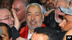 Rachid Ghannouchi (au centre) à son arrivée à l'aéroport international de Tunis, le 30 janvier 2011