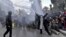 FILE: A Tunisian demonstrator flashes the V for victory sign as police fire water cannons during protests against President Kais Saied, on the 11th anniversary of the Tunisian revolution in the capital Tunis. Taken Jan. 14, 2022. -