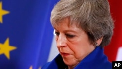 British Prime Minister Theresa May walks past the EU flag at the conclusion of an EU summit in Brussels, Nov. 25, 2018. European Union leaders gathered Sunday to seal an agreement on Britain's departure from the bloc next year.