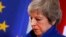 British Prime Minister Theresa May walks past the EU flag at the conclusion of an EU summit in Brussels, Nov. 25, 2018. European Union leaders gathered Sunday to seal an agreement on Britain's departure from the bloc next year.