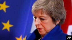 British Prime Minister Theresa May walks past the EU flag at the conclusion of an EU summit in Brussels, Nov. 25, 2018. 